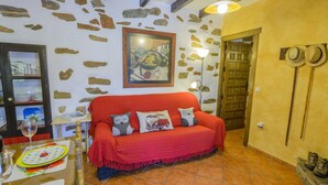 A cozy room with a red sofa, a stone wall, a painting, and a wooden door.