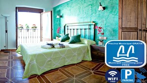 Une chambre avec un lit, une table de chevet, une armoire en bois, un mur vert et un panneau indiquant l’emplacement d’une piscine municipale gratuite.