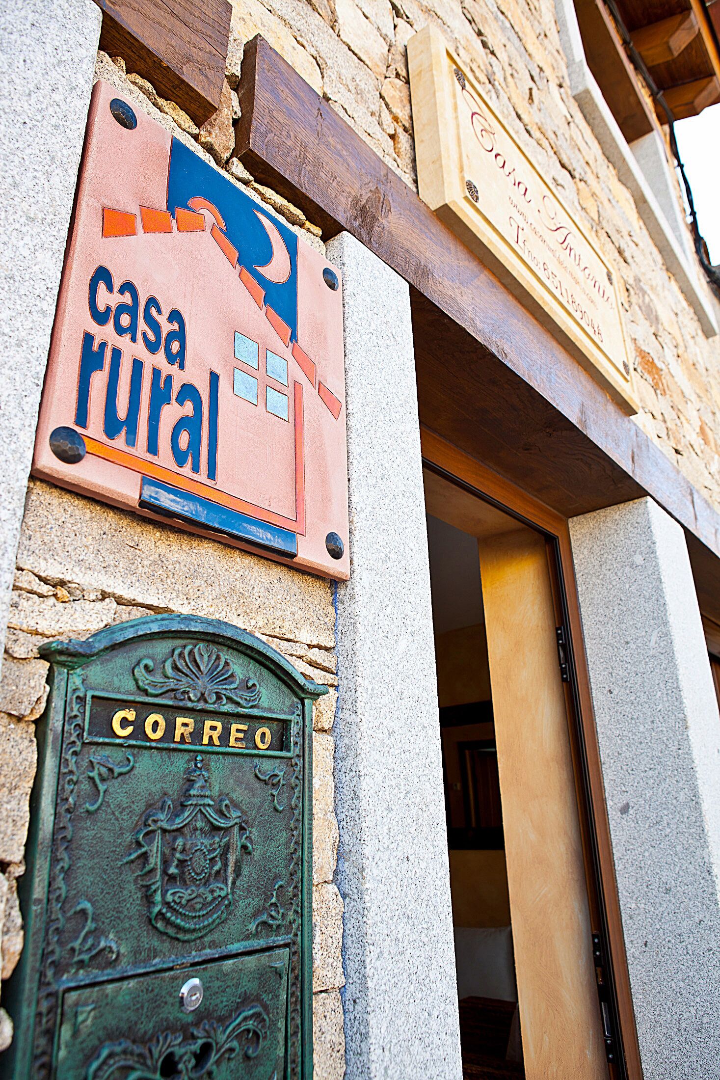 A rustic building with a sign reading "casa rural" and a green door labeled "correo".