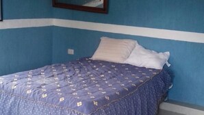 Ein Schlafzimmer mit einem Bett, einem an der Wand montierten Fernseher und einer weißen Deckenleuchte.