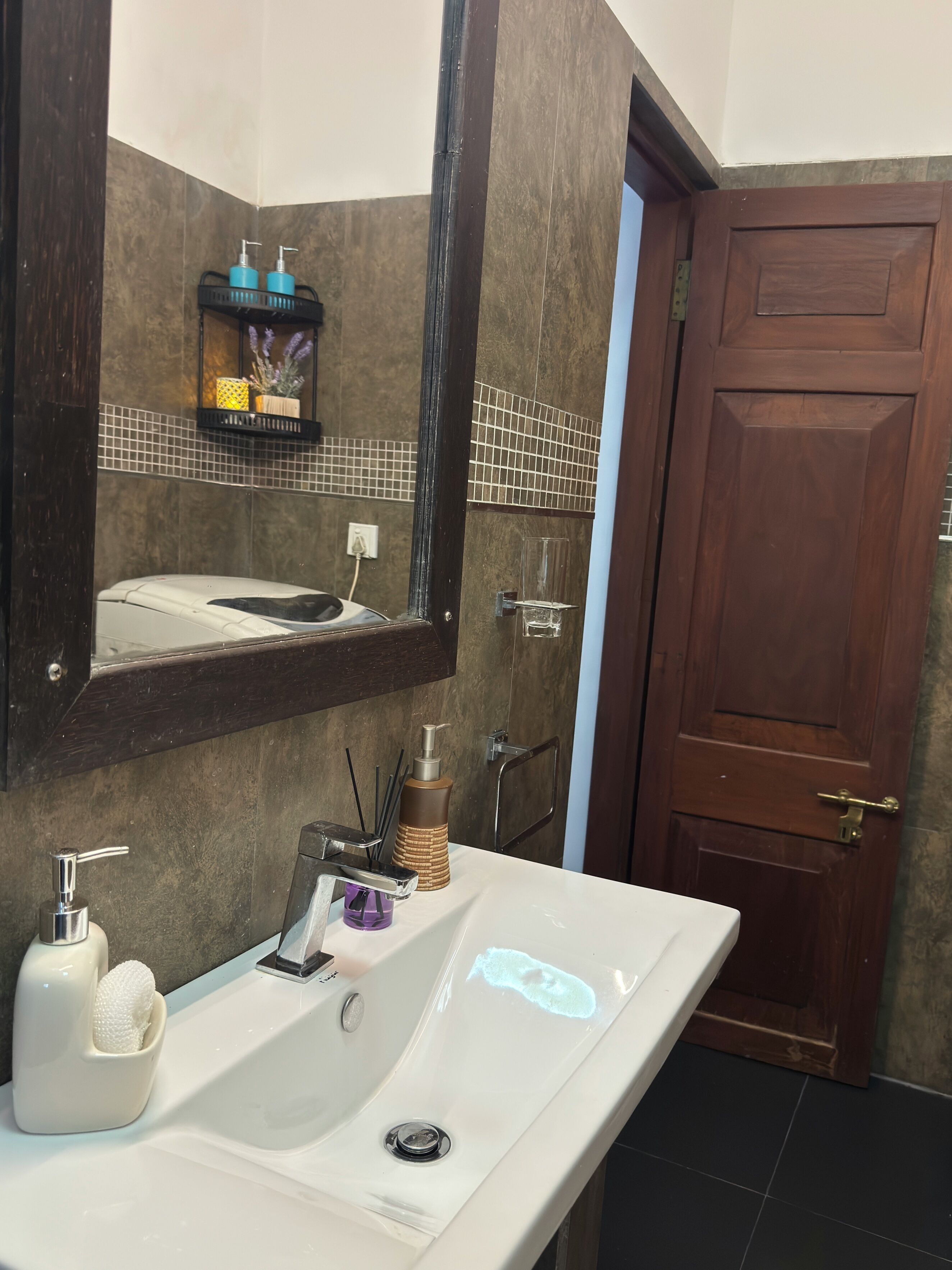 A bathroom with a white sink, a mirror, a towel rack, and a door.