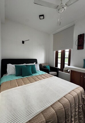 A bedroom with a bed, a nightstand, a window with blinds, and a ceiling fan. - fully furniture cinnamon apartment with privet roof garden (Panadura)