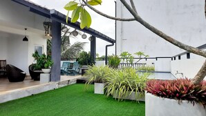 Un patio exterior moderno con césped artificial, asientos y plantas en macetas.