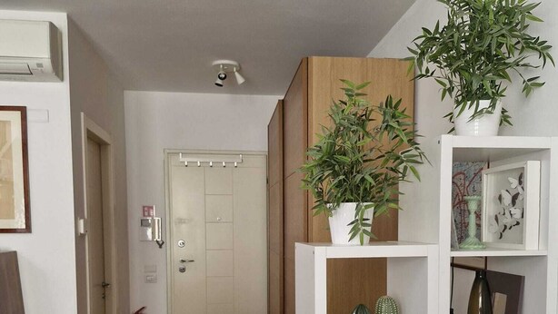 A modern living room with a white sofa, a small dining table, and a kitchen area with cabinets and a microwave. - In Florence, sunny and beautiful two-story flat, well connected to the center (Firenze)