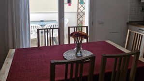 A dining area with a table, chairs, a vase with flowers, a clock, and a view through a sliding door. - In Florence, sunny and beautiful two-story flat, well connected to the center (Firenze)