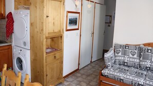 Un área de lavandería con lavadora y secadora, armarios de madera y un sofá con cojines estampados.