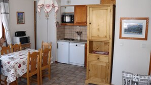 Una cocina compacta con una mesa de comedor, sillas, microondas, tostadora, lavavajillas y armarios de madera.