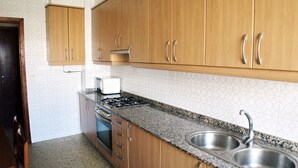 A kitchen with wooden cabinets, a granite countertop, a stove, and a double sink.