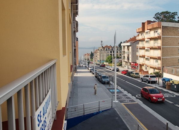 A street view with parked cars, a pedestrian, and buildings with balconies. - Caracas 11 apartment, 500 ms from Silgar beach (Sanxenxo)