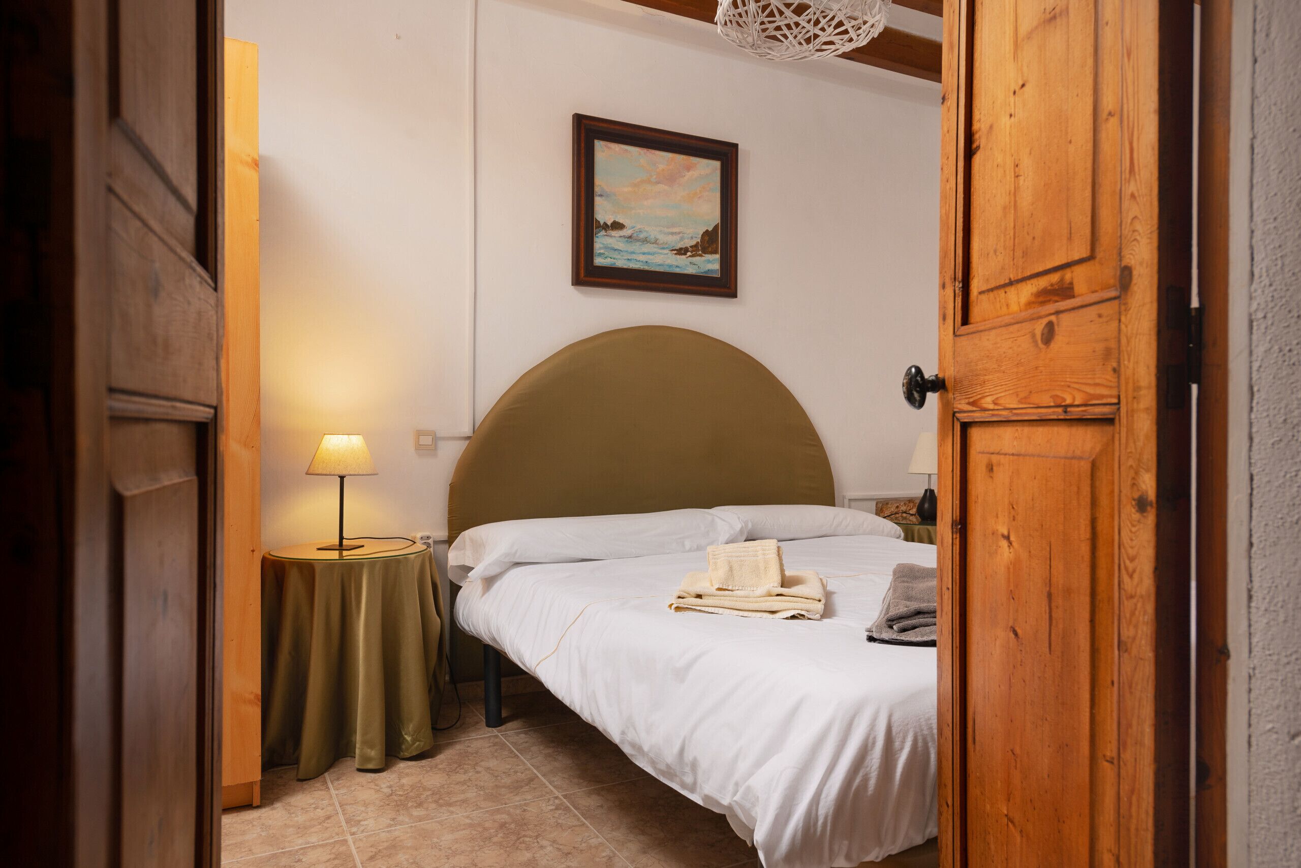 Une chambre à coucher avec un lit, une lampe de chevet, un tableau encadré au mur et une porte en bois.