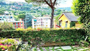 Un barrio residencial en una ladera con casas coloridas, un camino de piedra y abundante vegetación.