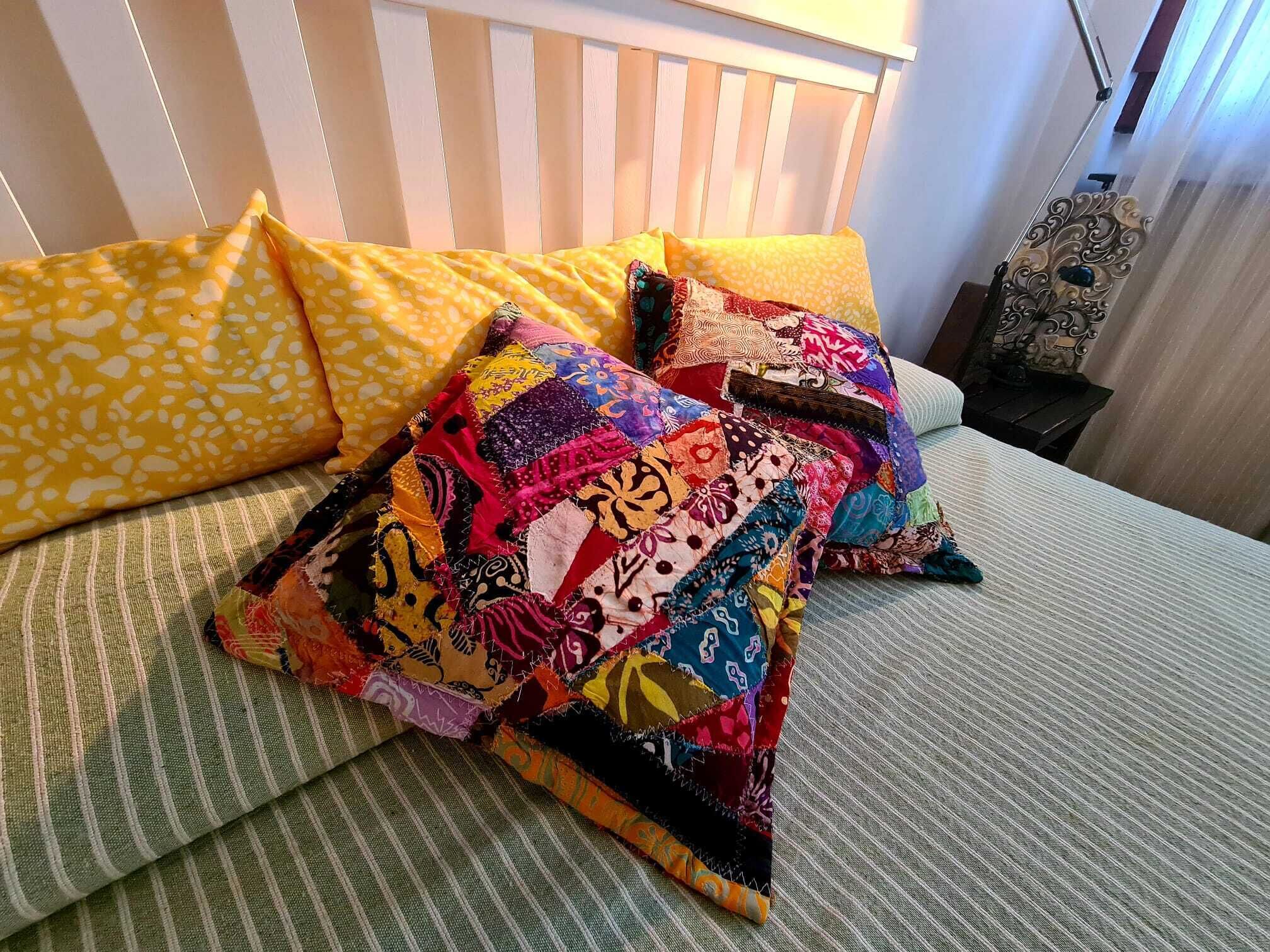 A bed with a green striped bedspread and multiple colorful pillows.