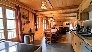 A wooden cabin with a kitchen, dining area, and large windows.
