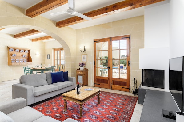 A living room with a sofa, coffee table, and fireplace. There is a dining area with a table and chairs in the background.