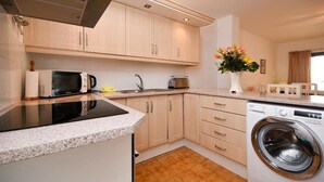 Une cuisine compacte équipée d’un four à micro-ondes, d’une cuisinière, d’un évier et d’un lave-linge.
