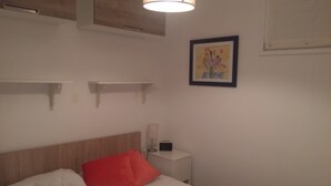 A bedroom with a bed, a bedside table, a lamp, and a framed picture on the wall.