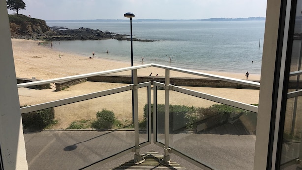 A balcony with a view of a beach and the sea.