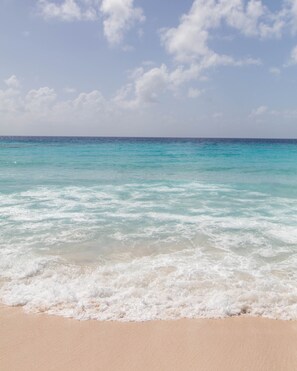 Ein Strand mit klarem türkisblauem Wasser und sandigem Ufer.