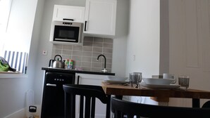 A compact kitchen with white cabinets, a black microwave, and a KRUG coffee machine. - Cottage in the Highest Village in Scotland (Wanlockhead)