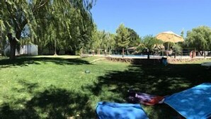 A park with a swimming pool, lounge chairs, and a person lying on a blanket. - Self catering Complejo Los Arenales for 4 people (Almagro)