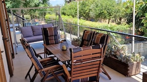 A patio with a wooden table and chairs, a swing, and a cushioned bench.