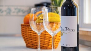 A bottle of wine with a label, two glasses, and a basket of fruits. - Cosy Apartment in Jardins Vale de Parra (Albufeira)