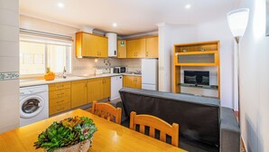 A compact kitchen with wooden cabinets, a built-in microwave, and a washing machine. - Cosy Apartment in Jardins Vale de Parra (Albufeira)