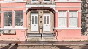 A pink building with a double door entrance, a nameplate above the doors, and a stone facade. - Luxury Seafront Apartment in Aberdovey -pets allowed/free parking -sleeps 8 (Aberdovey)