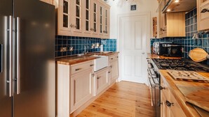 A modern kitchen with a stainless steel refrigerator, wooden cabinets, a tiled backsplash, and a gas stove. - Luxury Seafront Apartment in Aberdovey -pets allowed/free parking -sleeps 8 (Aberdovey)