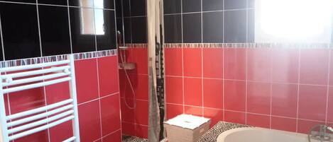 A bathroom with red and black tiles, a shower, a bathtub, and a towel rack.