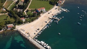 Vista aérea de una zona costera con un puerto deportivo, coches aparcados y edificios.