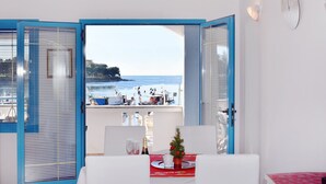 Una habitación con vista al mar, un pequeño árbol de Navidad y una mesa de comedor dispuesta para dos personas.