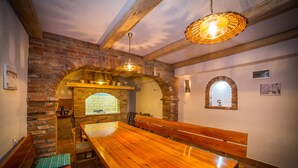 A rustic dining area with a wooden table and benches, brick walls, and a hanging light fixture. - Nice and fresh two with sea views, large balcony and pool access. (Rab)