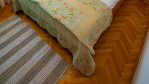 A neatly made bed with a floral bedspread, a wooden headboard, and a bedside lamp. - Nice and fresh two with sea views, large balcony and pool access. (Rab)