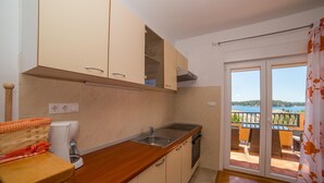 A kitchen with a wooden countertop, a sink, and cabinets. There is a balcony with a view of the sea. - Nice and fresh two with sea views, large balcony and pool access. (Rab)