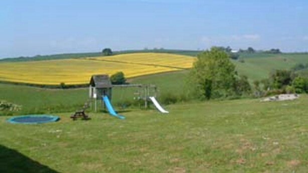 Een landelijk landschap met een speeltuin, inclusief een glijbaan en een klein onderkomen.