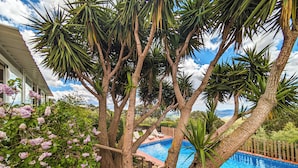 A pool area with a view of mountains, surrounded by trees and a house.