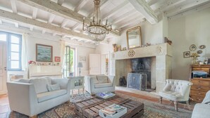 Amplia sala de estar con chimenea, un candelabro y una mesa de centro rústica.