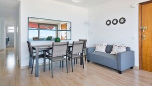Uma sala de estar moderna com uma mesa de jantar, sofá cinzento e porta de madeira.