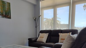 A living room with a sofa, a coffee table, and a painting on the wall.