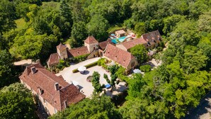 Vista aérea de una propiedad tradicional de estilo europeo con varios edificios, un patio central y una piscina.