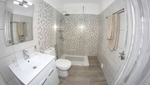 Et moderne badeværelse med vask, toilet og bruser.