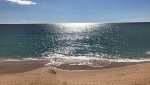 En strand med klart himmel og rolige bølger.