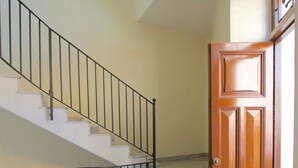 A staircase with a black metal railing, a wooden door, and a patterned doormat.
