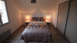Ein Schlafzimmer mit einem Bett, zwei Nachttischlampen, einem gemusterten Teppich und einem Fenster.