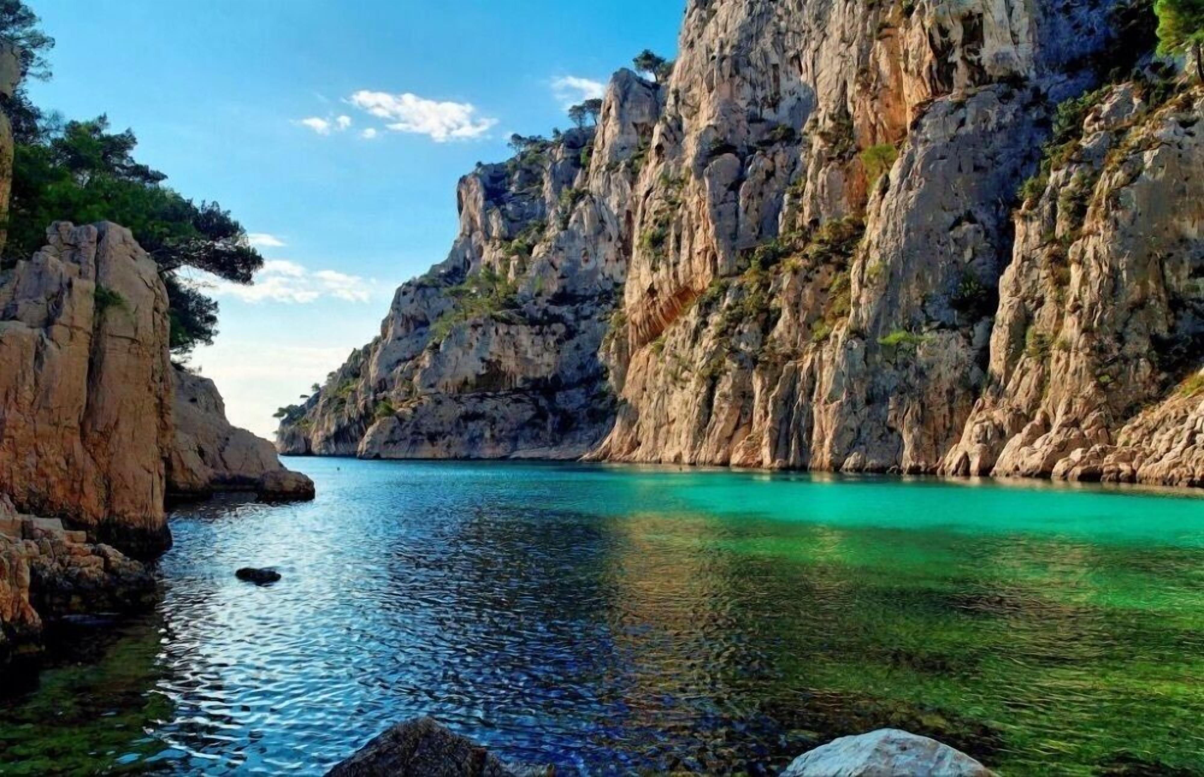 A coastal landscape with rocky cliffs and clear turquoise water.