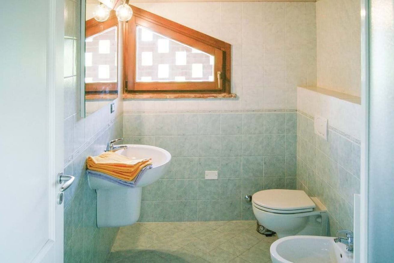 Une petite salle de bain avec une fenêtre, un lavabo, des toilettes et un bidet.