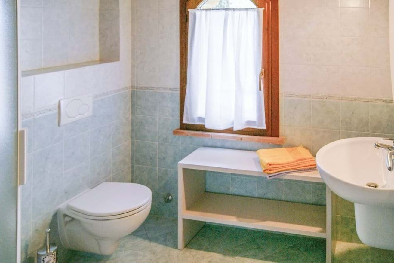 A small bathroom with a toilet, a sink, and a shelf with towels.