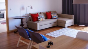 Een moderne woonkamer met een bank, een eettafel en een keuken op de achtergrond.