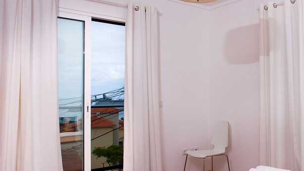 Een hotelkamer met een bed, een stoel en uitzicht op de stad.